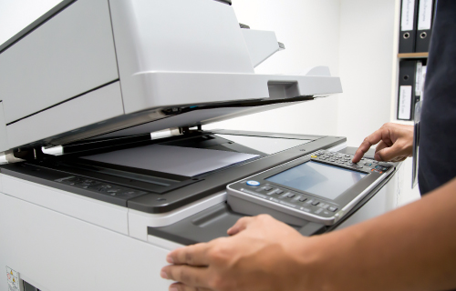 Mitarbeiter bedient einen Kopierer und Scanner im Copyshop